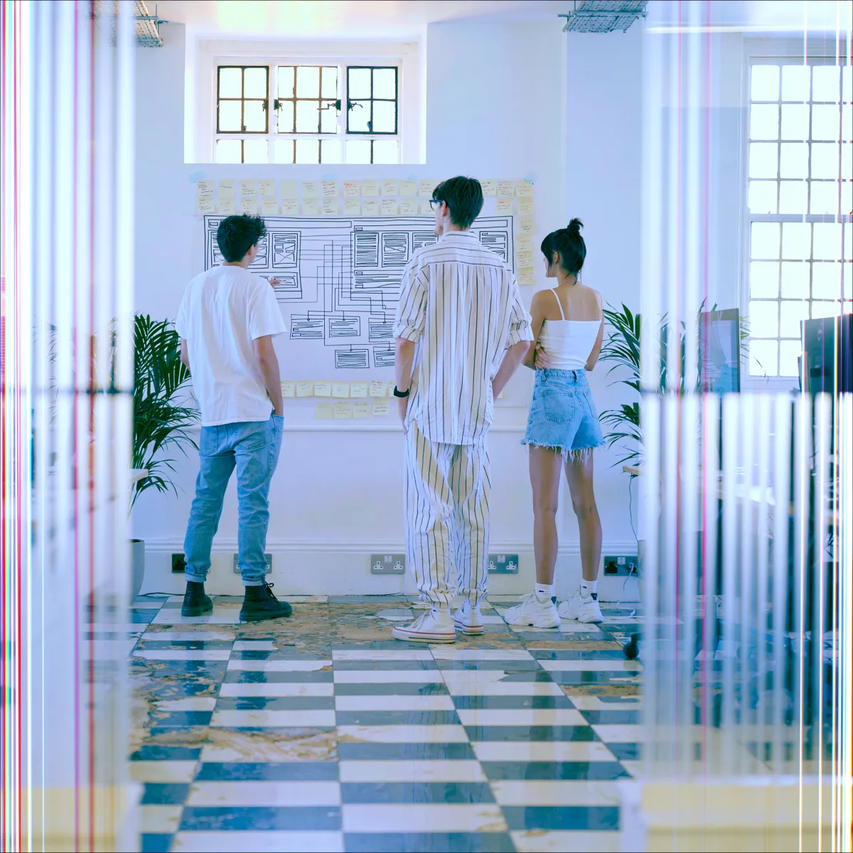 The team reviewing a wireframe wall, the frame torn vertically by scanline glitch